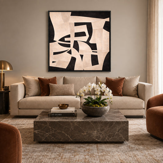 a modern living room with a large abstract painting on the wall above a beige sofa. The sofa is adorned with brown throw pillows and a bowl of white flowers on the coffee table. The room also includes a brown armchair and a marble coffee table.