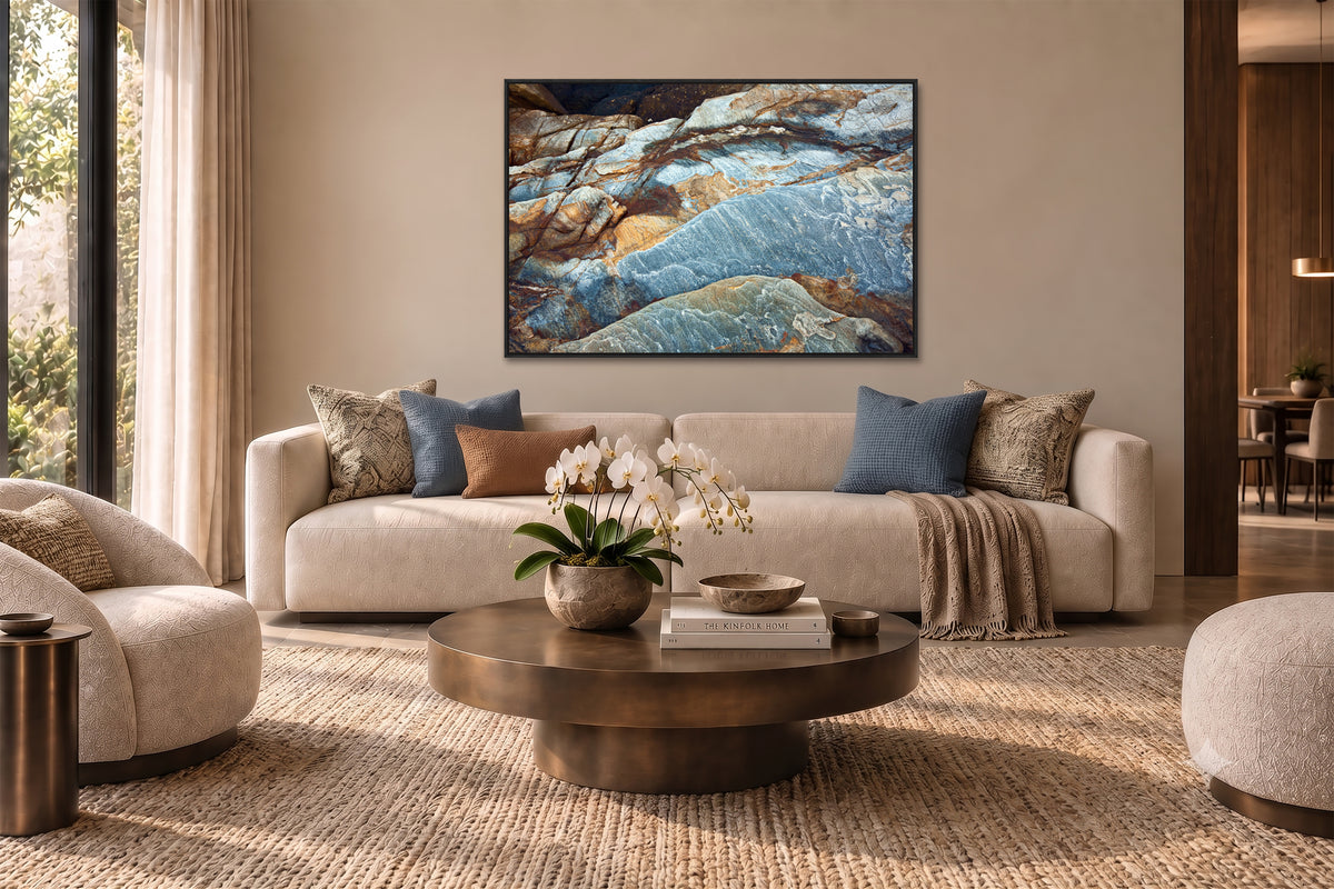a modern living room with a large window, a beige sofa, a round wooden coffee table, and a framed artwork on the wall.