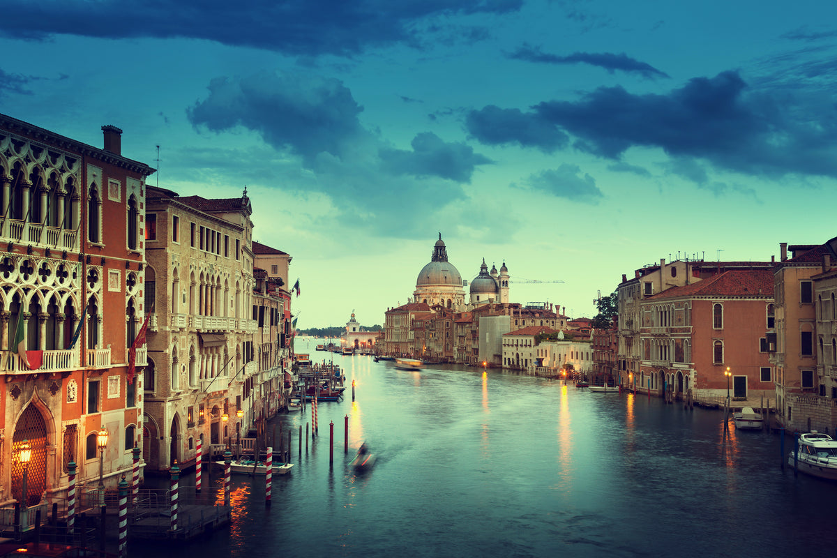 a picturesque view of the Grand Canal in Venice, Italy, with the iconic dome of St. Mark's Basilica standing out against the cloudy sky. The canal is lined with colorful buildings and boats, creating a vibrant and lively atmosphere.