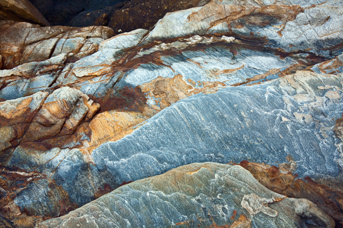 a close-up view of a rocky surface with a mix of blue, orange, and brown hues, suggesting a natural landscape.