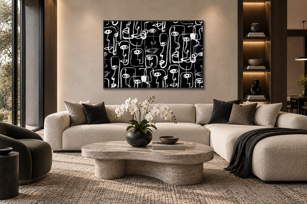 a modern living room with a large abstract painting featuring black and white lines on the wall above a white sofa. The sofa is positioned in front of a round coffee table, which has a vase of white flowers on it. The room also includes a bookshelf, a potted plant, and a large window that allows natural light to fill the space.